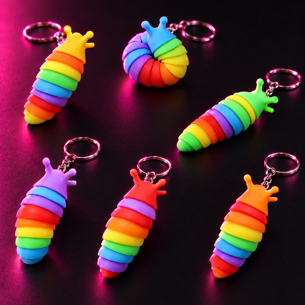 Six rainbow mini fidget slug keychains on a dark surface